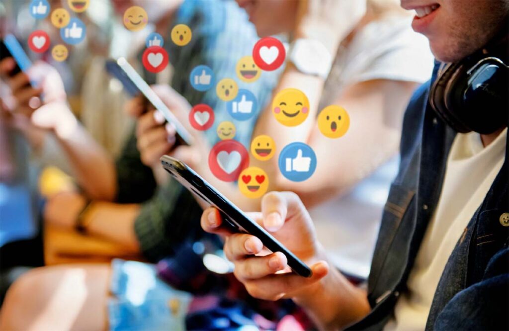 People using smartphones with floating social media reaction icons like likes, hearts, and emojis, representing digital engagement on Influencer Marketing Hub.