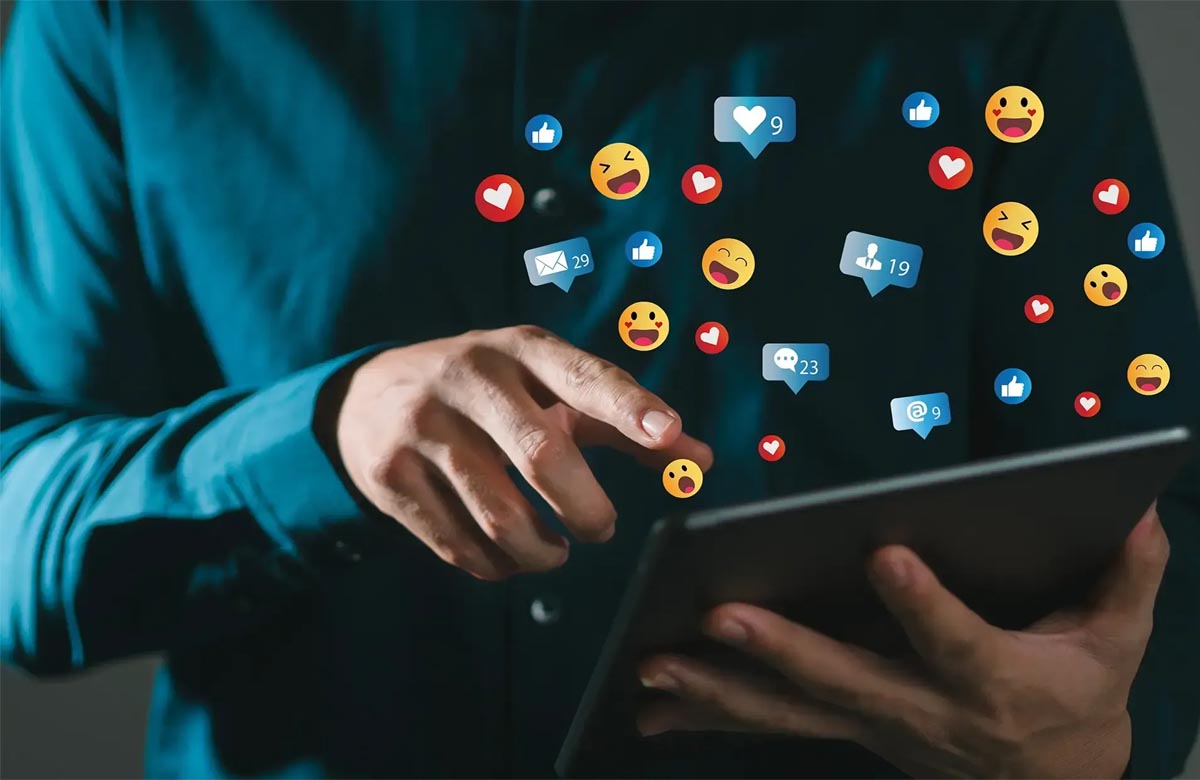 Person interacting with a tablet as social media icons and reactions float above the screen, representing the dynamic role of a Social Media Influencer.